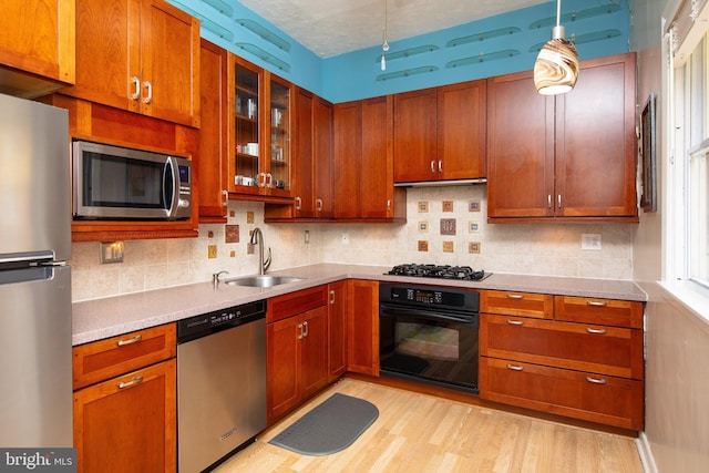 kitchen featuring a sink, under cabinet range hood, tasteful backsplash, appliances with stainless steel finishes, and light countertops