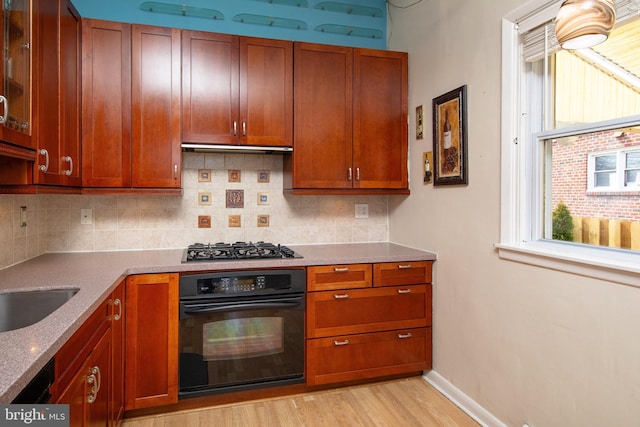 kitchen featuring light wood-type flooring, gas stovetop, tasteful backsplash, and oven