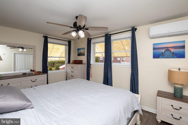 bedroom featuring dark wood finished floors, ceiling fan, a wall mounted AC, and baseboards