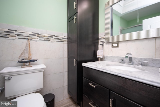 bathroom with vanity, tile walls, and toilet