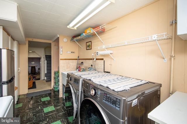 laundry area featuring tile walls, laundry area, and washer and clothes dryer