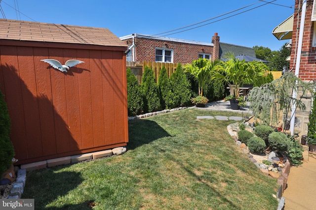 view of yard featuring a storage shed, an outbuilding, and fence