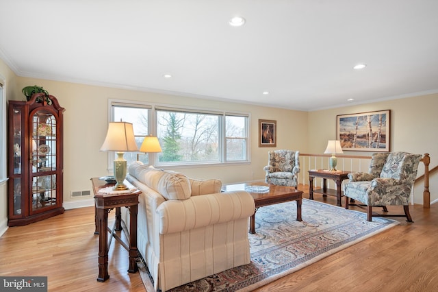 living room featuring crown molding, recessed lighting, baseboards, and light wood finished floors