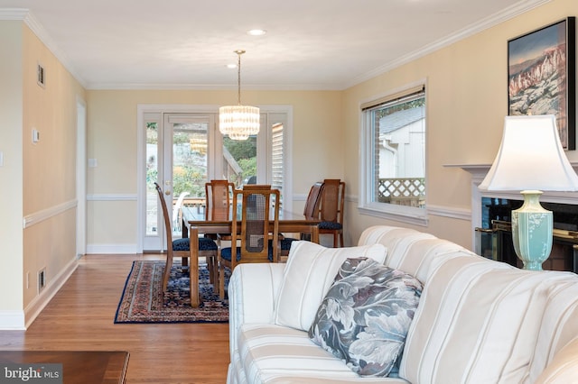 living room with visible vents, an inviting chandelier, wood finished floors, and crown molding