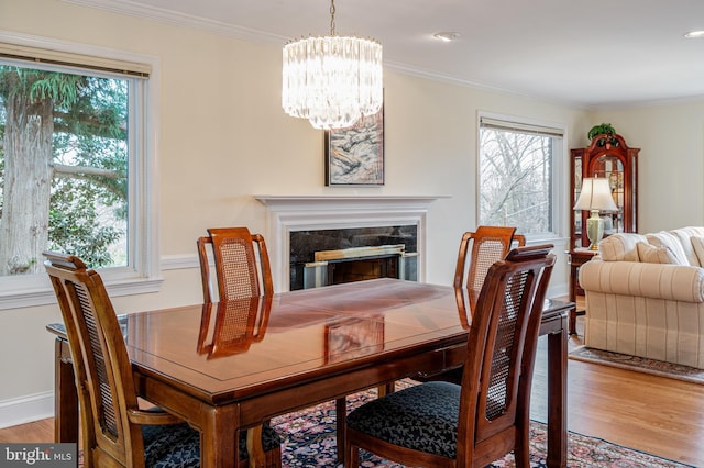 dining space featuring light wood-type flooring, a chandelier, a healthy amount of sunlight, and ornamental molding