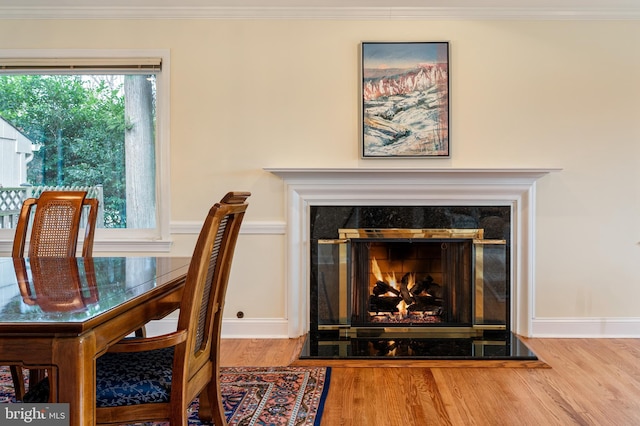 dining area with wood finished floors, a lit fireplace, and ornamental molding