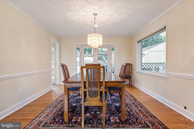 dining room with an inviting chandelier, crown molding, and light wood-style floors