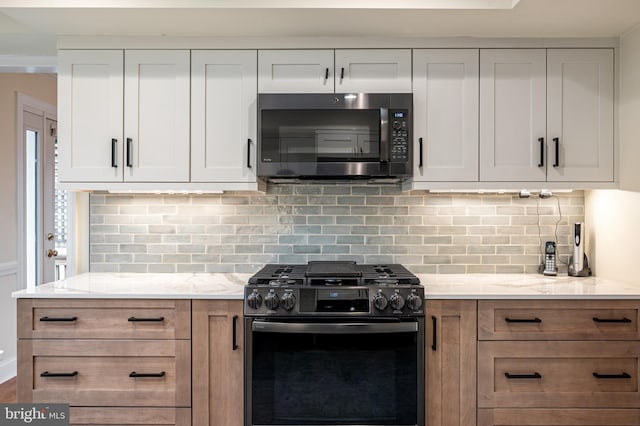 kitchen with light stone counters, decorative backsplash, and gas stove