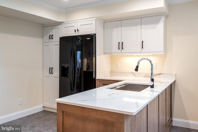 kitchen with black fridge, a sink, light stone counters, a peninsula, and crown molding