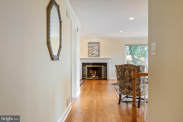 hall featuring visible vents, baseboards, ornamental molding, and light wood finished floors