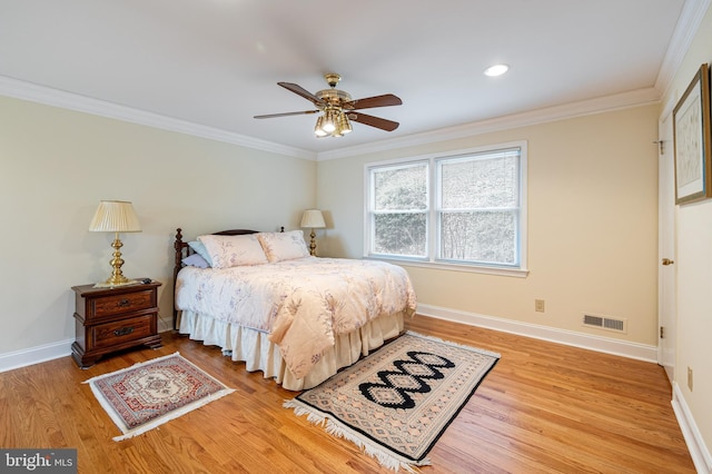 bedroom with light wood-type flooring, visible vents, baseboards, and crown molding