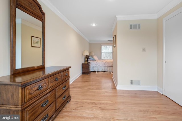 hallway featuring baseboards, visible vents, light wood finished floors, and ornamental molding