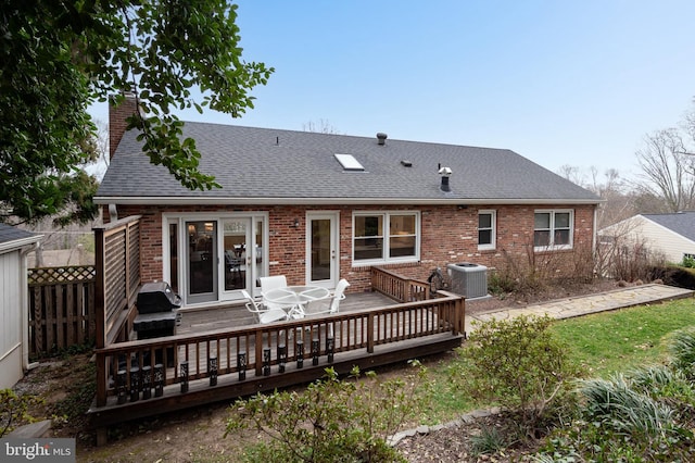 rear view of house featuring central air condition unit, fence, roof with shingles, brick siding, and a chimney