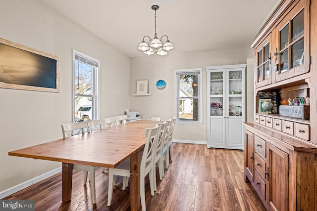 dining area featuring light wood finished floors, baseboards, and an inviting chandelier