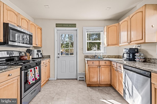 kitchen featuring light brown cabinetry, a sink, stainless steel appliances, light tile patterned floors, and light stone countertops