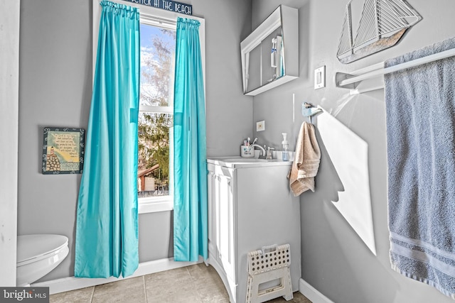 bathroom featuring tile patterned flooring, toilet, baseboards, and a sink