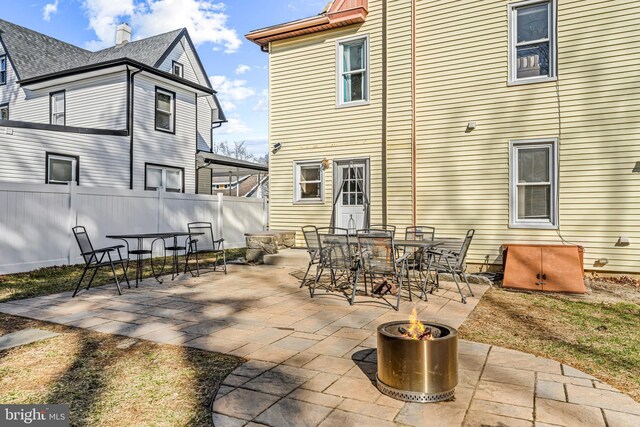 back of property with outdoor dining area, a patio, a fire pit, and fence