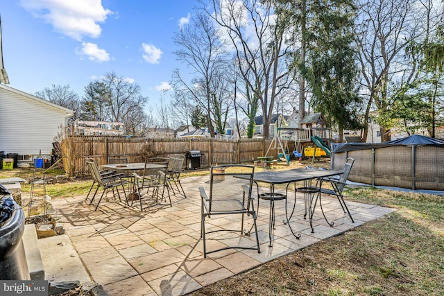 view of patio with a pool, a fenced backyard, outdoor dining area, and a playground