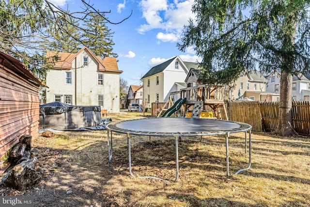 view of yard with a pool, fence, a playground, a trampoline, and a residential view