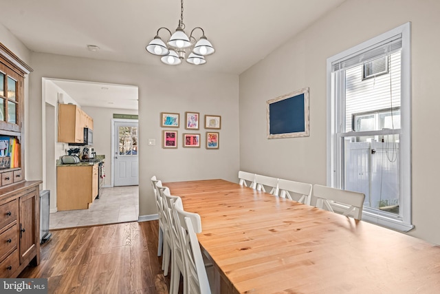 dining room with baseboards, light wood-type flooring, and an inviting chandelier