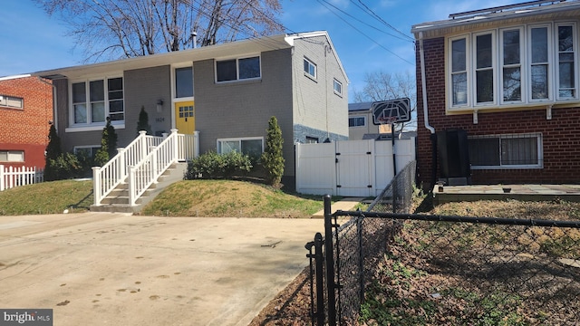 view of front of house with fence, brick siding, and a gate