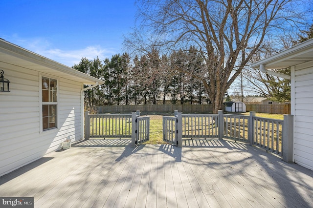 wooden deck with an outbuilding, a storage unit, a fenced backyard, and a lawn