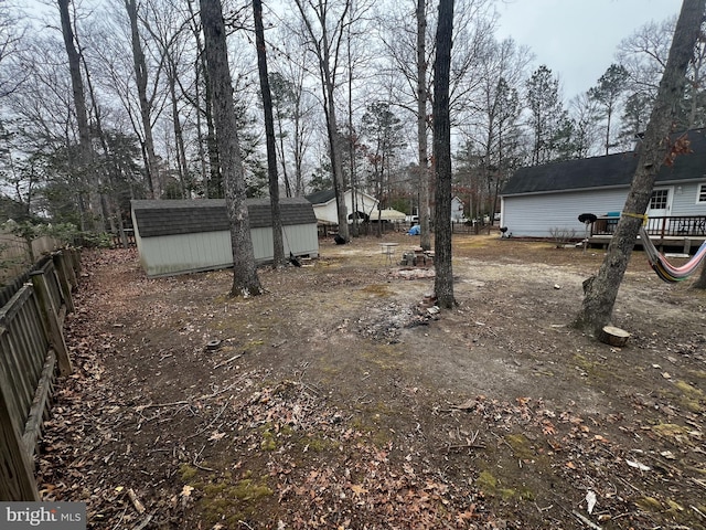 view of yard featuring a storage unit, an outdoor structure, and fence