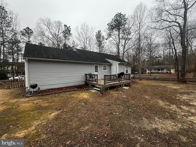 rear view of house featuring fence and a wooden deck