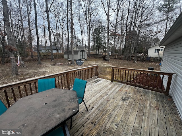 wooden deck featuring an outbuilding, a shed, outdoor dining space, and a fenced backyard