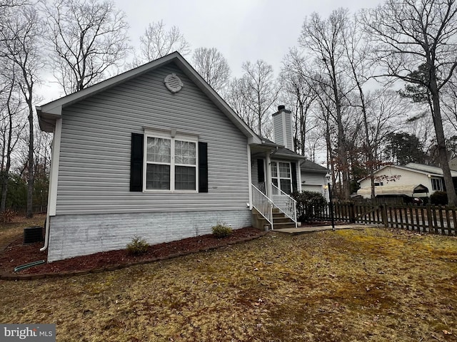 view of front of home featuring central AC unit, fence, and a chimney