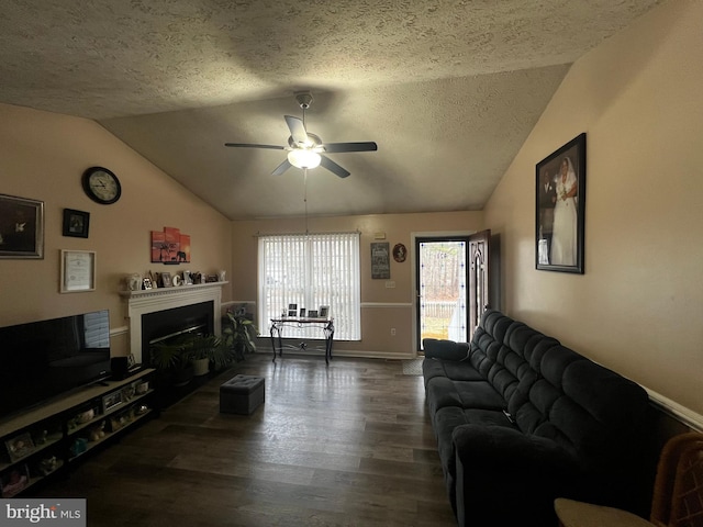 living room featuring vaulted ceiling, a fireplace, wood finished floors, a textured ceiling, and a ceiling fan