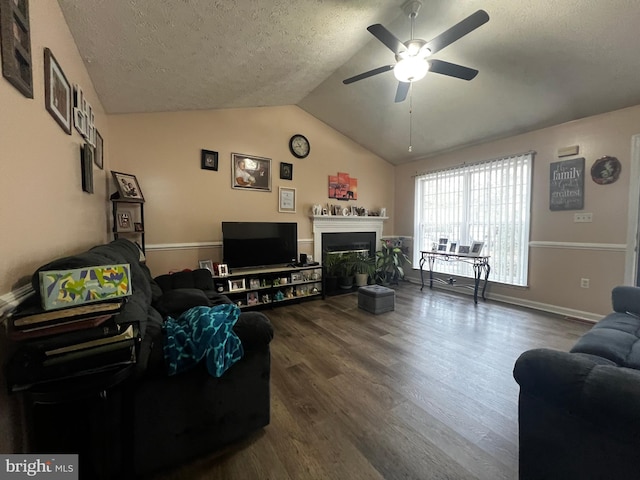 living room featuring vaulted ceiling, a fireplace, wood finished floors, a textured ceiling, and a ceiling fan