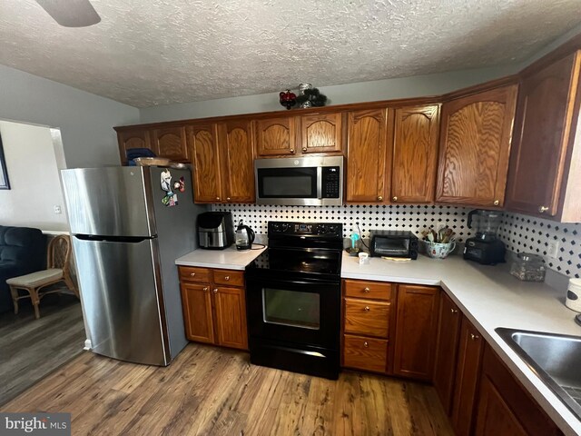 kitchen with light countertops, light wood finished floors, appliances with stainless steel finishes, and a sink