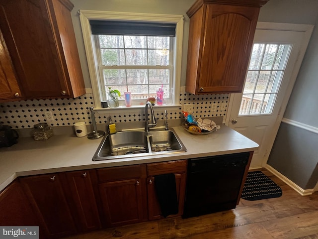 kitchen featuring dishwasher, light countertops, a healthy amount of sunlight, and a sink