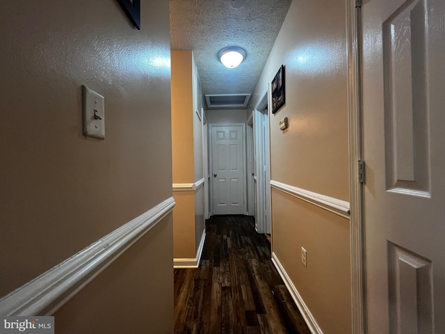 corridor featuring baseboards, a textured ceiling, and dark wood-style floors