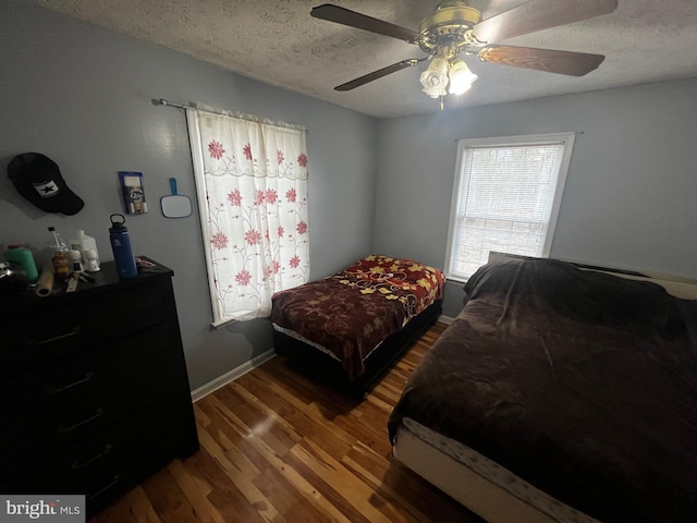 bedroom with ceiling fan, a textured ceiling, baseboards, and wood finished floors