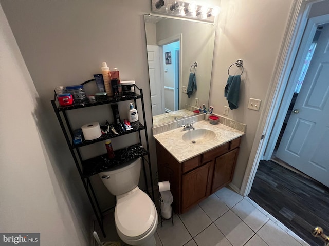 half bath featuring tile patterned floors, toilet, and vanity