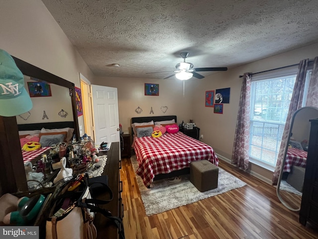 bedroom with baseboards, a textured ceiling, wood finished floors, and a ceiling fan