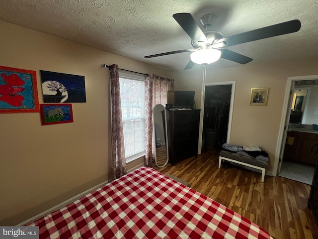 bedroom featuring baseboards, a textured ceiling, ceiling fan, and wood finished floors