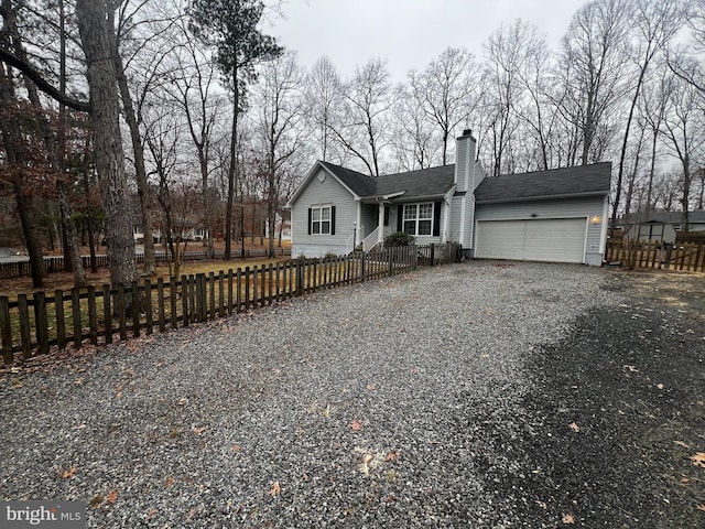 view of front of house with gravel driveway, an attached garage, a fenced front yard, and a chimney