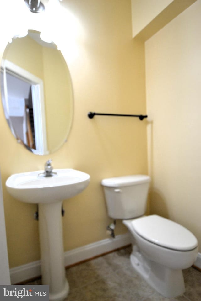 half bathroom with tile patterned flooring, toilet, and baseboards