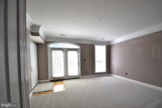 carpeted spare room featuring visible vents, baseboards, and ornamental molding