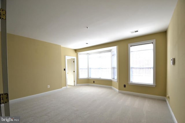 unfurnished room with visible vents, light carpet, and baseboards