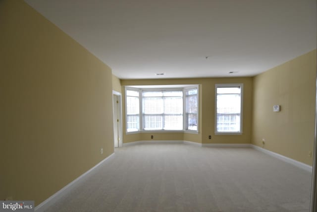 spare room with baseboards and light carpet