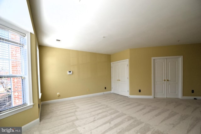 unfurnished room featuring plenty of natural light, baseboards, and light carpet