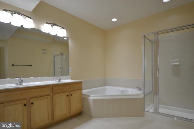 bathroom featuring a sink, a garden tub, a stall shower, and double vanity