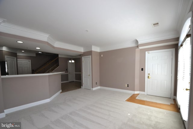 foyer entrance with visible vents, ornamental molding, baseboards, light colored carpet, and stairs