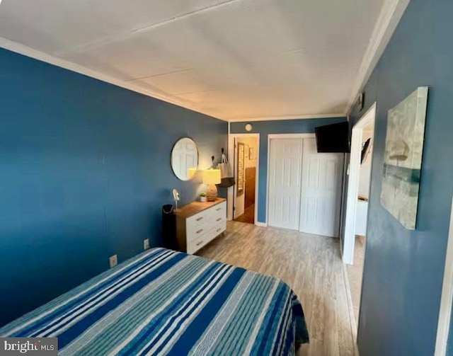 bedroom with a closet, crown molding, and wood finished floors