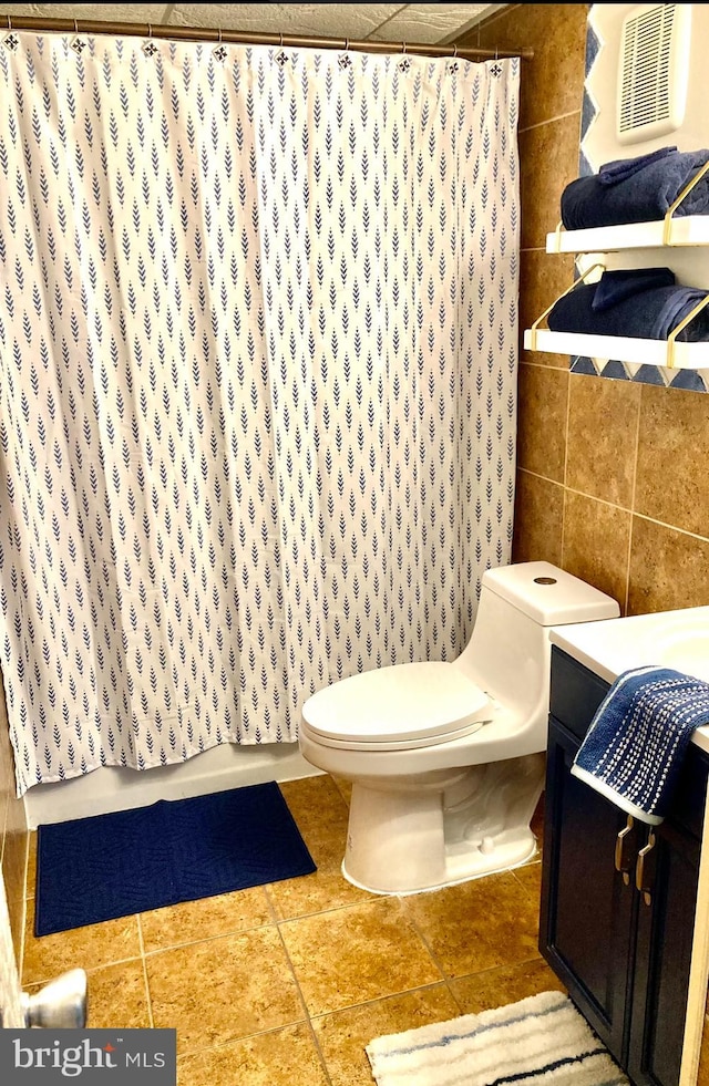 bathroom with a shower with shower curtain, tile walls, toilet, and tile patterned floors