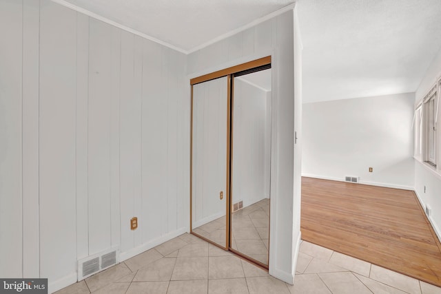 unfurnished bedroom featuring visible vents, light tile patterned flooring, and crown molding